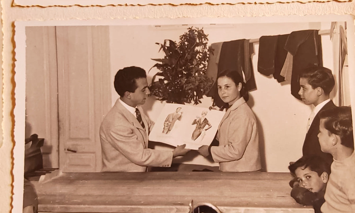 A man and his wife showing his fashion designs to a group of people.