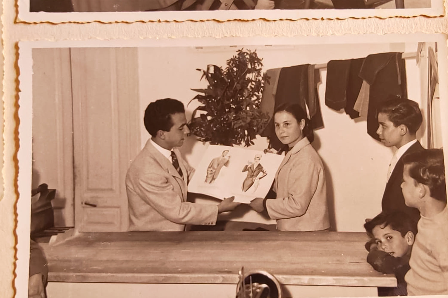A man and his wife showing his fashion designs to a group of people.